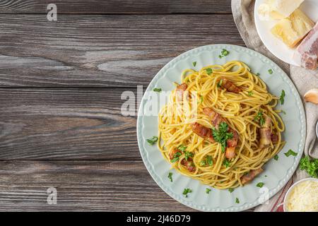 Pasta spaghetti carbonara con pancetta, pancetta, uova, parmigiano su sfondo ligneo. Cucina italiana. Vista dall'alto Foto Stock