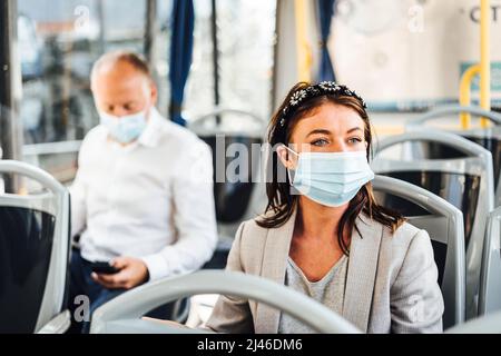Viaggiatori che indossano maschere protettive che viaggiano con autobus pubblico Foto Stock
