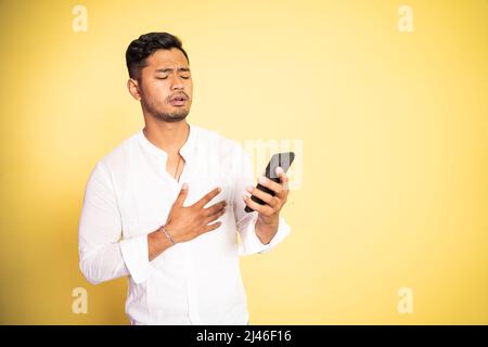 il giovane uomo asiatico ha scioccato mentre guardava il video utilizzando il telefono cellulare Foto Stock