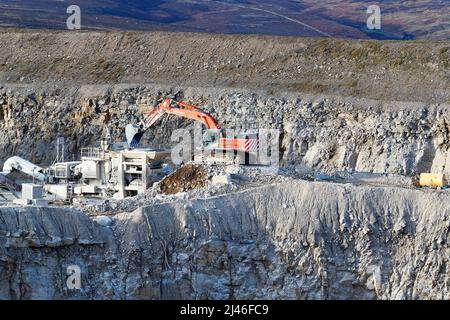 Un escavatore Hitachi 470 che lavora alla cava di Coldstones, situata sulla collina di Greenhow a 1400 piedi sopra il livello del mare, è una delle cave più alte in Brittan Foto Stock