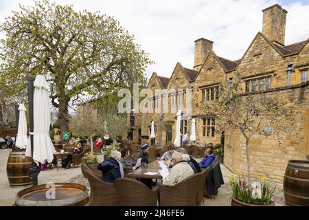 Cotswold Hotel; persone che si siedono a bere nel cortile del Lygon Arms, un 14th Century Hotel, Broadway Village, Cotswolds Worcestershire Regno Unito Foto Stock