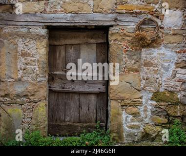 Un'antica porta in legno in una casetta a Poffabro, storico borgo medievale della Val Colvera in provincia di Pordenone, Friuli-Venezia Giuli Foto Stock