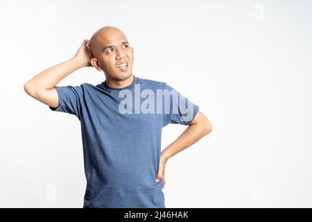 confuso uomo di calva asiatico che tiene la sua testa calva Foto Stock