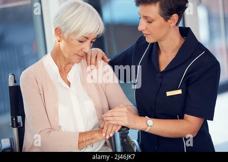 Presto le cose miglioreranno. Scatto corto di una giovane infermiera femmina che consolava una donna anziana seduta in una sedia a rotelle in una casa di cura. Foto Stock