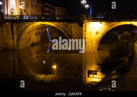 Scena stradale durante la serata con ponte vecchio illuminato che attraversa il fiume Segura in Murcia in Spagna Foto Stock