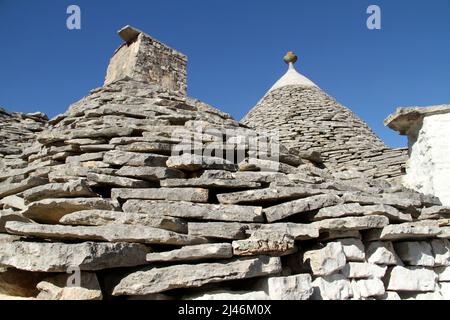 Il tetto conico, con pinnacolo e camino, di una tradizionale casa trullo di pietra di 500 anni ad Alberobello, Italia. Foto Stock