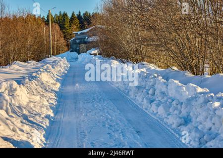 Strada sterrata sgevata di neve nella giornata invernale soleggiata. Foto Stock