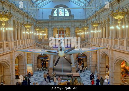 Glasgow, Scozia, Regno Unito 12th aprile 2022. Il famoso fuoco d'uccello appeso al soffitto della galleria sopra la folla si fa ammirare da un giovane pilota al livello dell'occhio vista della galleria. Il tempo umido, la stagione delle vacanze e una quantità sufficiente di bambini a causa delle vacanze scolastiche hanno visto il museo di Kelvingrove e le gallerie d'arte piene di uscite con locali e turisti nello spazio vibrante. Credit Gerard Ferry/Alamy Live News Foto Stock