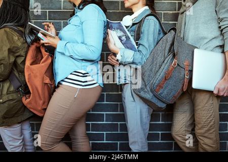 Formazione di una coda ordinata. Scatto ritagliato di un gruppo di studenti universitari irriconoscibili che si trovano in un corridoio del campus. Foto Stock