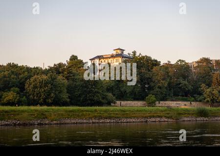 Grande villa vicino al fiume Elba. La luce del tramonto splende sulla facciata dell'edificio. Grandi alberi di fronte alla casa. Una sera durante l'estate. Foto Stock