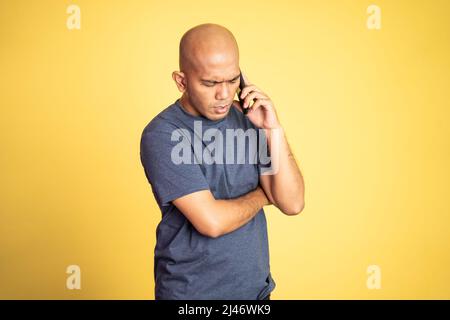 triste asiatico calvo uomo che ascolta il telefono Foto Stock