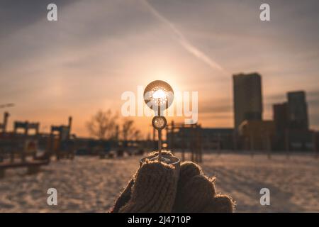 il sole che tramonta brilla attraverso un cerchio in una bolla di sapone bastone in inverno Foto Stock