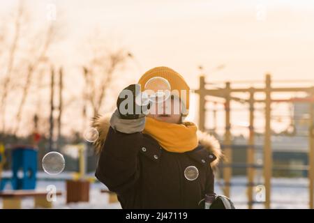 carino ragazza soffia bolle di sapone in inverno Foto Stock