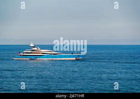 L'enorme mega yacht è ormeggiato in mare al largo della costa azzurra in giorno di sole, il corrimano cromato, riflesso del sole su bordo lucido di Foto Stock