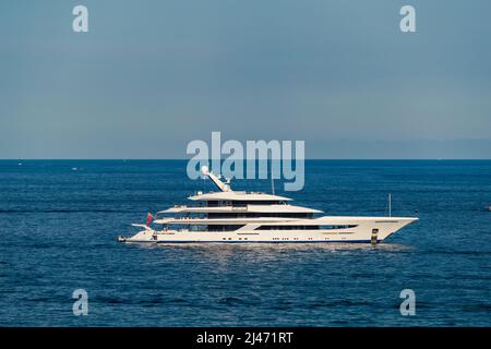 L'enorme mega yacht è ormeggiato in mare al largo della costa azzurra in giorno di sole, il corrimano cromato, riflesso del sole su bordo lucido di Foto Stock