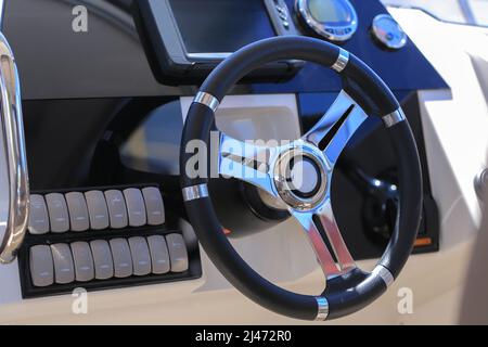 Primo piano del volante dell'imbarcazione a motore e cruscotto con dispositivi di navigazione Foto Stock