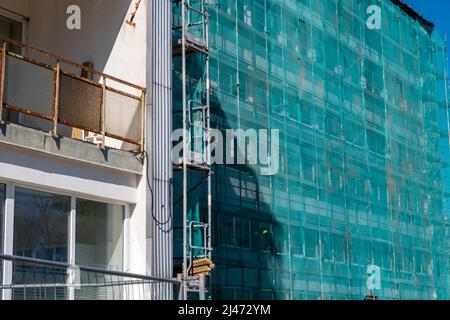 Rete di sicurezza di protezione verde avvolta per edifici in costruzione. Foto Stock