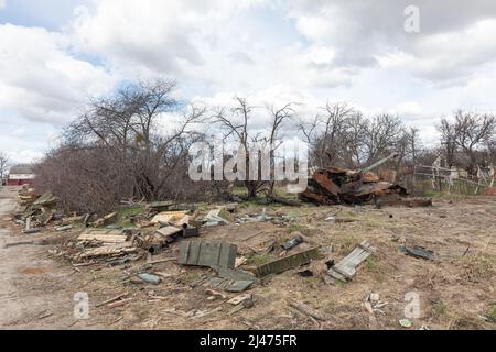 ANDRIIVKA, UCRAINA - 12 aprile 2022: Serbatoio bruciato sul lato della strada. Le attrezzature abbandonate, le conchiglie e le scatole vuote di armi si trovano in mezzo al campo lungo la strada vicino Andriivka dopo il ritiro delle truppe russe. Caos e distruzione lungo le strade dell'Ucraina Foto Stock