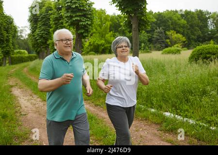 Una coppia di anziani felici si ritirò correndo nel parco all'aria aperta. Foto Stock