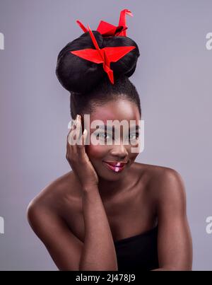 Il trucco ingrandisce la bellezza che già esiste. Studio ritratto di una bella giovane donna che indossa asiatico ispirato trucco e posa con origami contro Foto Stock