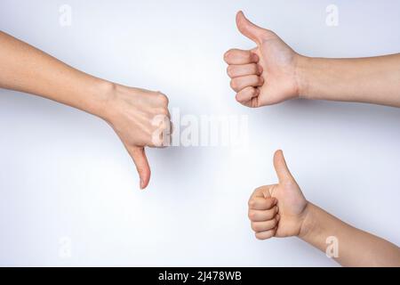 le mani mostrano i pollici su e giù su uno sfondo bianco Foto Stock