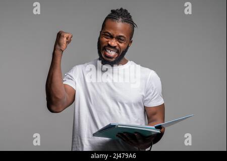 Simpatico studente maschile che gioisce del suo successo Foto Stock