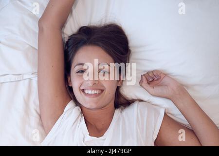 Relax la vita è bella. Scatto di una giovane femmina che si sveglia a letto a casa. Foto Stock