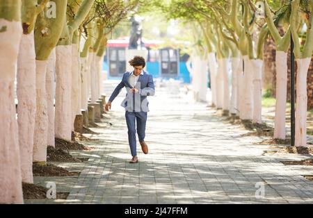 Ho sudato i soldi e la banca è la mia doccia. Colpo pieno di un giovane uomo d'affari che precipita per strada e controlla il suo orologio contro una città Foto Stock