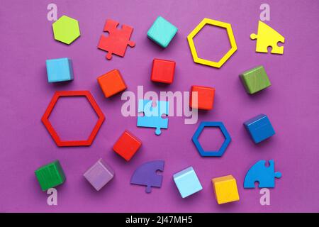 Cubi colorati con blocchi e pezzi di puzzle su sfondo viola Foto Stock