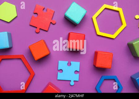 Cubi colorati con blocchi e pezzi di puzzle su sfondo viola Foto Stock