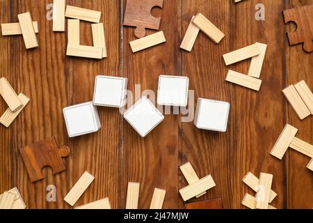 Cubi con blocchi e pezzi di puzzle su sfondo di legno Foto Stock