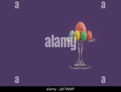 Semplice concetto di pasqua creativa di uova colorate dipinte in colori pastello. Dessert di Pasqua. Uova di diverse dimensioni sono decorate con paillettes e arran Foto Stock