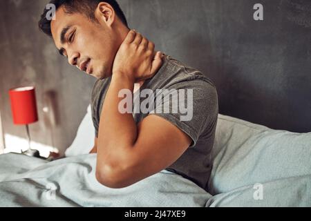 Chiunque ha ottenuto il numero di una buona clinica di sonno. Colpo di un giovane uomo che avverte dolore al collo dopo essersi svegliato a letto a casa. Foto Stock