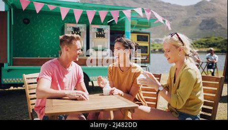 Il sabato è per gelato con gli amici. Shot di un gruppo di amici che mangiano gelato e si appendono fuori. Foto Stock