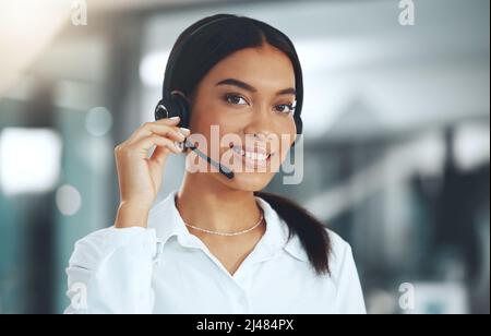 Come posso essere d'aiuto oggi. Scatto di un giovane agente del call center in piedi da solo nel suo ufficio. Foto Stock