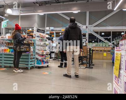Kirkland, WA USA - circa aprile 2022: Vista di uomini e donne in coda per i chioschi self-check all'interno di un negozio di alimentari Whole Foods Foto Stock
