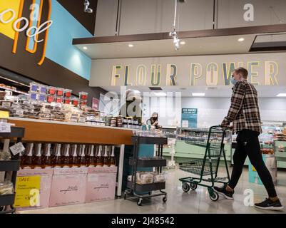 Kirkland, WA USA - circa Aprile 2022: Vista degli uomini e delle donne che acquistano nel reparto panetteria all'interno di un negozio di alimentari Whole Foods. Foto Stock