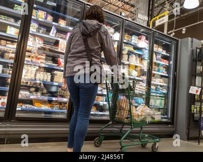 Kirkland, WA USA - circa Aprile 2022: Vista di una donna adulta che naviga nella sezione Frozen Foods in un negozio di alimentari Whole Foods. Foto Stock