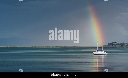 Arcobaleno su uno yacht, il lungomare di Motueka, il sandspit Motueka sullo sfondo, Motueka, Tasman regione, isola sud, Aotearoa / Nuova Zelanda. Foto Stock