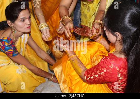 Bride indù indiano con pasta curcuma applicata sul suo volto divertirsi con la sua famiglia e amici. Concetto di matrimonio indiano Foto Stock
