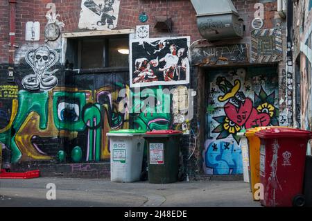 Street art giustapposta con bidoni municipali per la raccolta dei rifiuti in AC/DC Lane, Melbourne, Australia Foto Stock