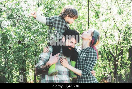 La famiglia cammina insieme attraverso il campo di fiori primaverili. Famiglia felice di trascorrere il tempo insieme in giardino. Famiglia a piedi in campo agricolo. Foto Stock