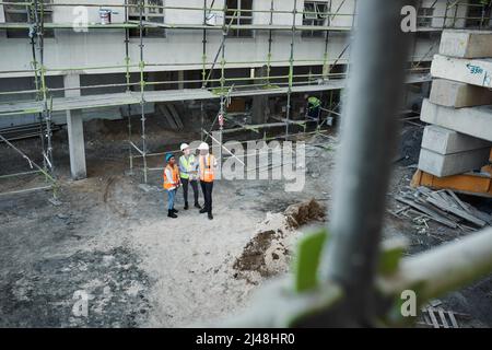 Il settore delle costruzioni è in piena espansione. Immagine di un gruppo di appaltatori di edifici che hanno una discussione mentre lavorano in un cantiere. Foto Stock