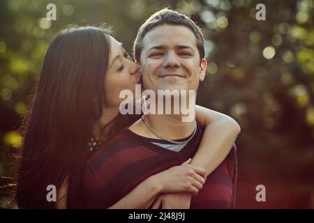 Le coppie più felici sanno come Buon divertimento. Shot di una giovane coppia affettuosa che si gode un giro di piggyback all'aperto. Foto Stock