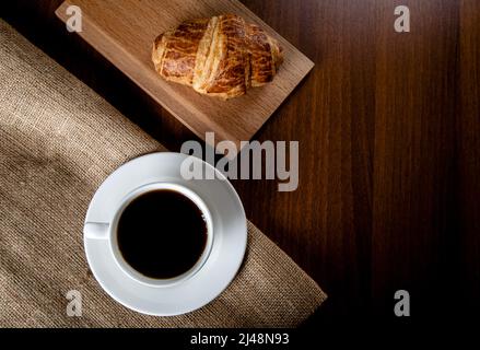 Tazza bianca piena di caffè e croissant, vista dall'alto Foto Stock