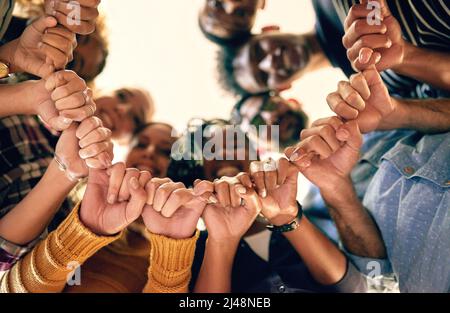 Niente può strappare la nostra determinazione a parte. Inquadratura ad angolo basso di un gruppo di persone che uniscono le mani. Foto Stock