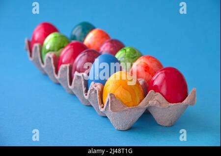 Colorate uova di Pasqua in scatola di cartone su sfondo blu Foto Stock