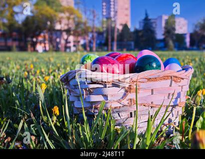 Uova di Pasqua in cestino di vimini sul prato verde Foto Stock