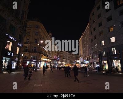 Vista sulla strada dello shopping Graben di notte vicino a Stephansplatz nel centro storico di Vienna, Austria, con gente a piedi e negozi illuminati. Foto Stock