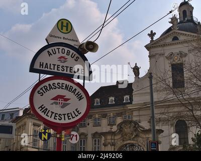 Segnaletica stradale alla stazione degli autobus e del tram Unteres Belvedere nel centro storico di Vienna, Austria con il logo di Wiener Linien e vecchio edificio. Foto Stock